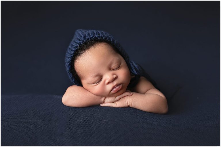 Newborn picture with navy background and navy knit cap. Studio located in Sierra Vista, Arizona. 