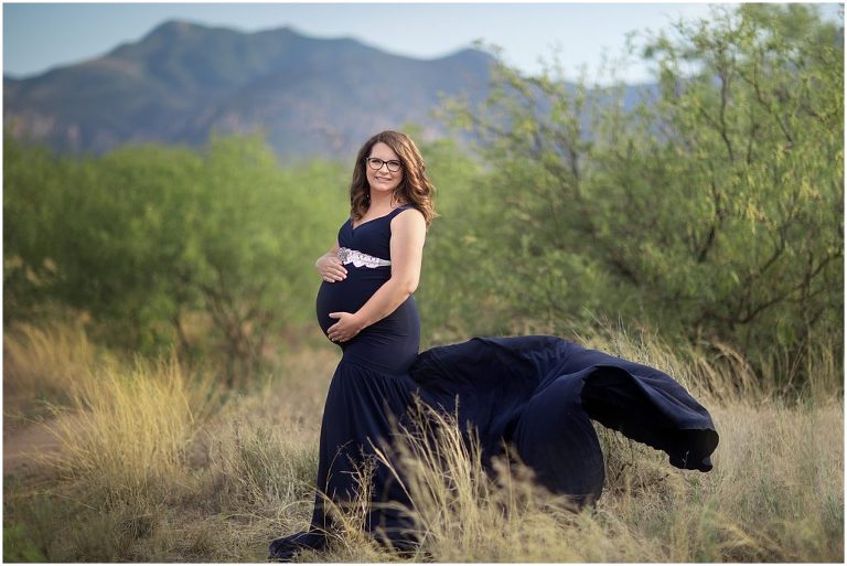 Maternity pose in navy gown with green landscape in Sierra Vista Arizona.