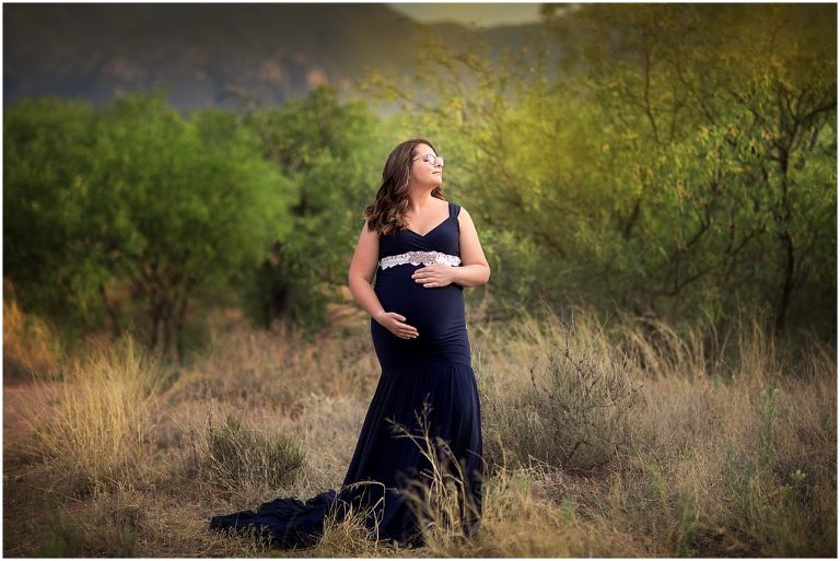 Maternity pose in navy gown with green landscape in Sierra Vista Arizona.