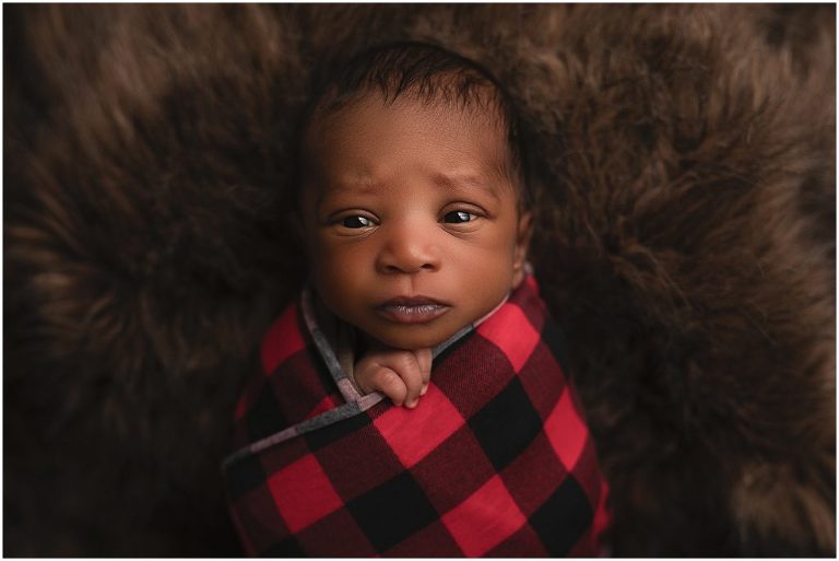 newborn boy photo in checkered red and black blanket